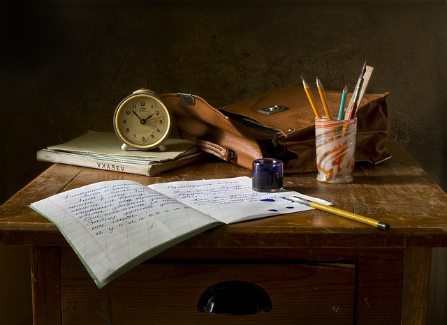 机の上にノートや筆記具が置いてあり、手紙を書いています